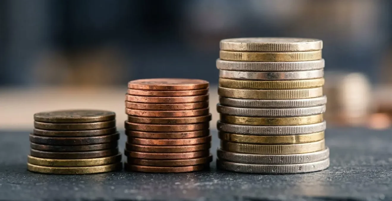 Détail macro de pièces de monnaie de différentes tailles empilées en équilibre parfait, symbolisant un portefeuille diversifié.